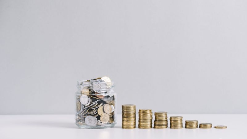 glass-jar-full-money-front-decreasing-stacked-coins-against-white-background