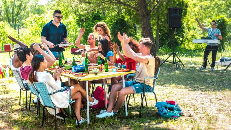 Happy friends having fun together at barbeque pic nic party - Multiracial young people at open air food festival - Youth friendship concept with guys and girls eating at garden barbecue