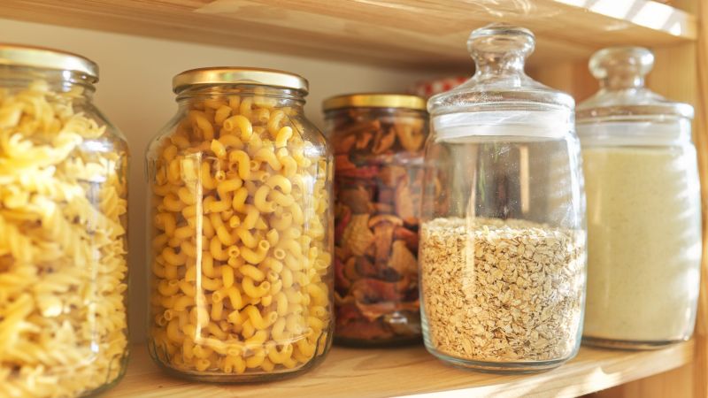 Wooden shelves in pantry for food storage, grain products in storage jars.